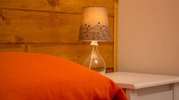 Un mur en bois, une lampe dont le pied est décoré de motifs rappelant des branches, et un coussin orange.