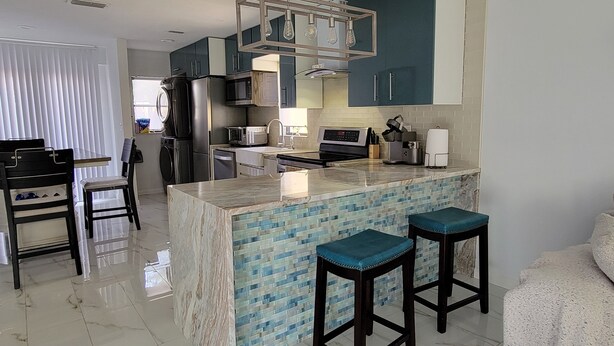 Una cocina moderna con una isla de mármol, taburetes de bar y electrodomésticos de acero inoxidable.