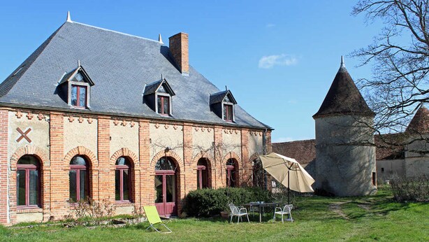 Ein historisches Gebäude mit steilem Dach, Backsteinfassade und Rundbogenfenstern.