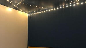 Un dormitorio con cama, almohadas blancas y luces de adorno.
