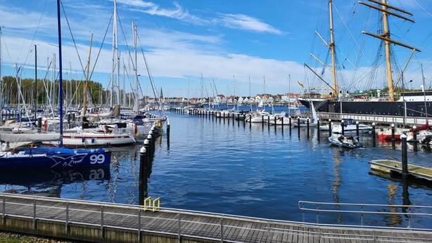 A marina with various boats docked, including sailboats and yachts.