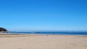 A wide sandy beach with a clear blue sky and calm sea.