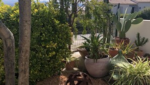 Un jardin agrémenté de diverses plantes en pot, d’une sculpture en métal et d’un arbre.