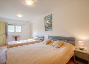 A bedroom with two beds, a painting on the wall, and a window with curtains. - Homerez - Apt. in Moltifao, great view. (Moltifao)