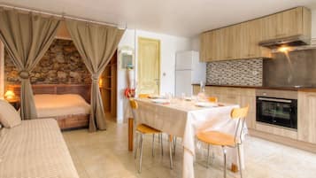 Une cuisine moderne avec un coin repas, un mur en pierre et un lit agrémenté de rideaux.