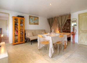 A dining area with a table set for four, a sofa, a bookshelf, and a map on the wall. - Homerez - Apt. in Moltifao, great view. (Moltifao)