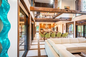 Relax in a spacious living area with a large sofa and dining table, surrounded by natural light and a view of the outdoors.