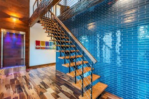 Stunning staircase leads to an upper level, flanked by a vibrant mosaic wall and herringbone-patterned floor.