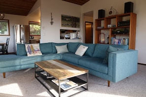 Una sala de estar con un sofá azul verdoso, una mesa de centro de madera y una estantería.