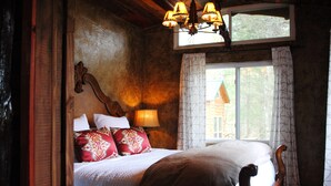 Un lit en bois avec une tête de lit, une lampe de chevet et une fenêtre avec des rideaux.