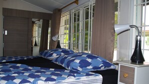 Een slaapkamer met een bed, twee nachtkastjes, een lamp en een raam met gordijnen.