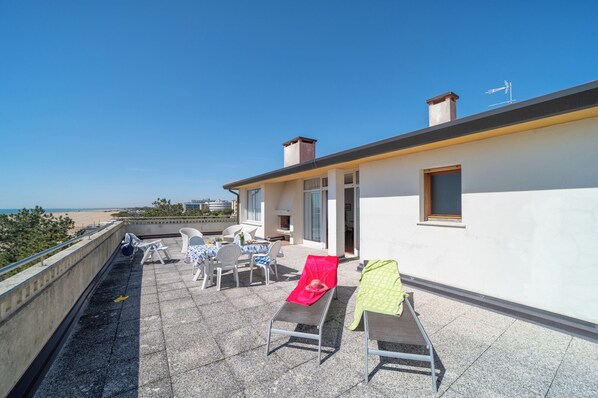 A rooftop terrace with outdoor seating and a view of the beach.