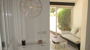 Una sala de estar moderna con un reloj de pared grande, un sofá, una mesa de centro y un mueble bajo.