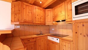 Ett kompakt kök med träskåp, en inbyggd mikrovågsugn och en diskmaskin.