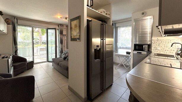 A modern kitchen with a built-in refrigerator, a dining area with a table and chairs, and a balcony with a view of the outdoors.