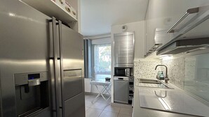 A compact kitchen with a built-in refrigerator, a microwave, and a sink.