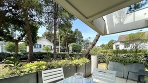 An outdoor patio with a table and chairs, surrounded by greenery and trees.