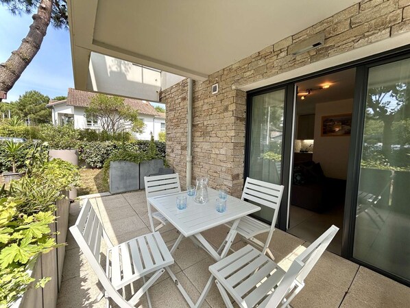 A patio with a table and chairs, a stone wall, and a sliding glass door leading to an indoor area.