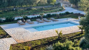 Un área de piscina con sillas de descanso y un sendero de piedra.