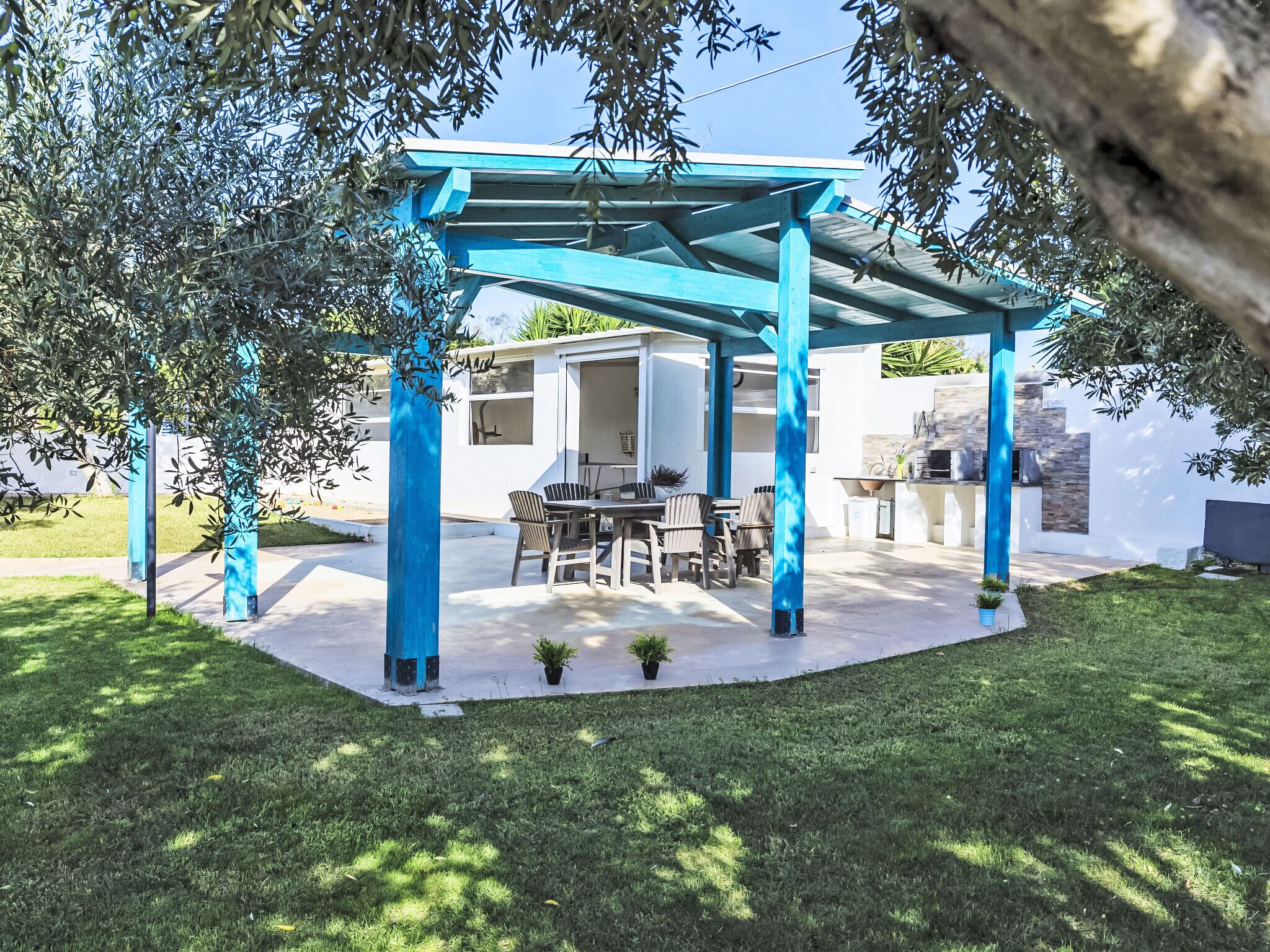 A covered patio with a dining area and barbecue setup.