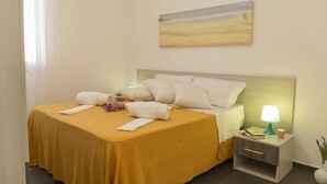 A hotel room with a bed, a nightstand with a lamp, and a painting on the wall.