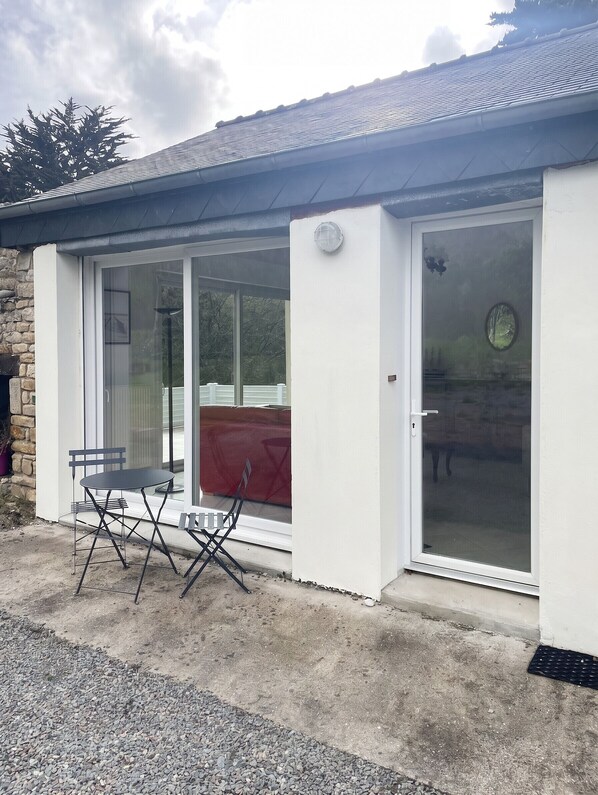 Un bâtiment doté d’un patio couvert, d’une porte-fenêtre coulissante et d’une petite table avec des chaises.