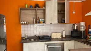 Ett kompakt kök med en inbyggd diskmaskin, en brödrost och en kaffebryggare.