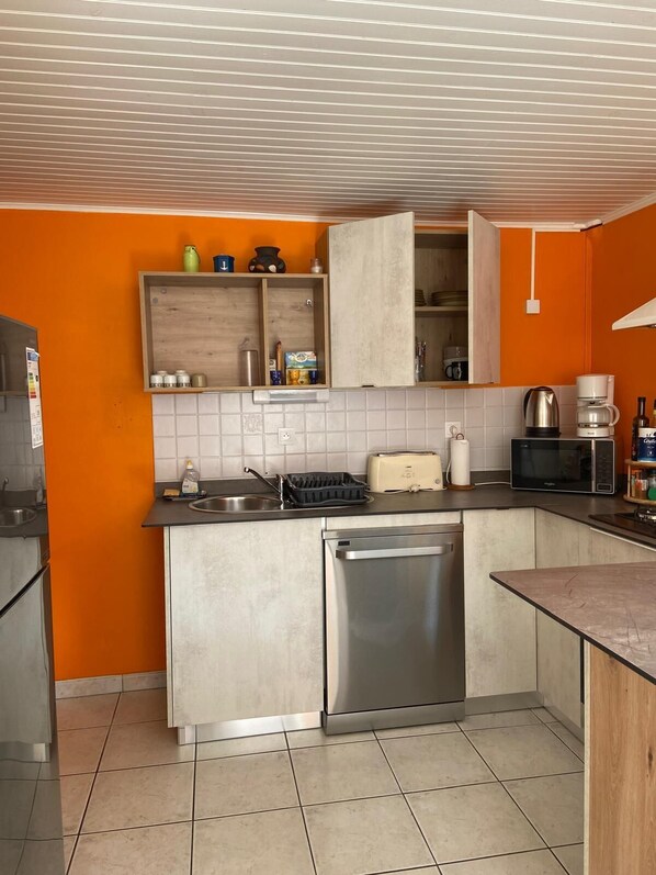 A compact kitchen with a built-in dishwasher, a toaster, and a coffee maker.