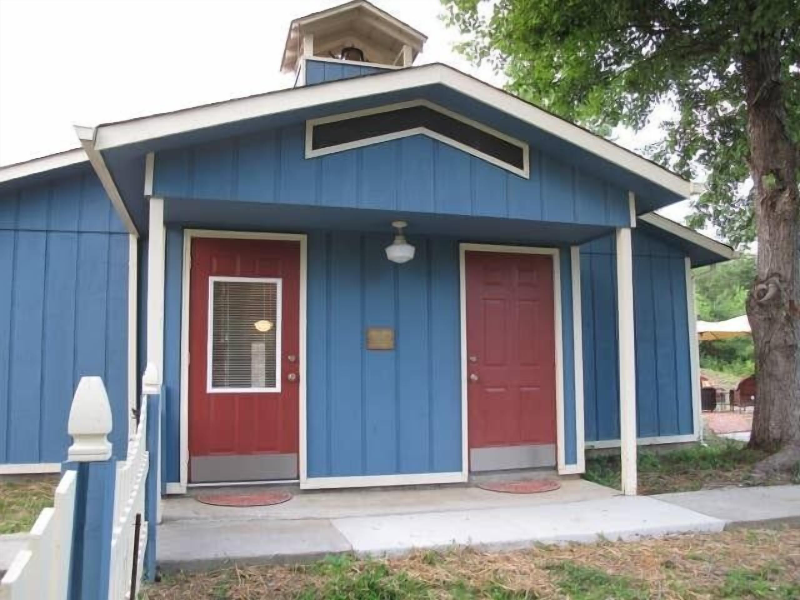A blue building with a red door and a small porch.