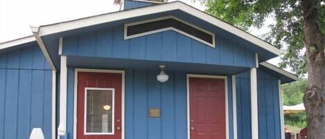 A blue building with a red door and a small porch.