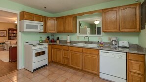 Una cocina con armarios de madera, microondas, estufa, fregadero y lavavajillas.