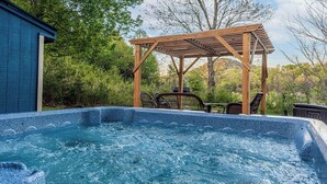 Tinaco con pérgola de madera y sillas, rodeado de vegetación exuberante.