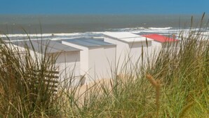 A coastal building with a flat roof and a red section, surrounded by grass. - Havenhuys 304 with balcony by Interhome (Bredene)