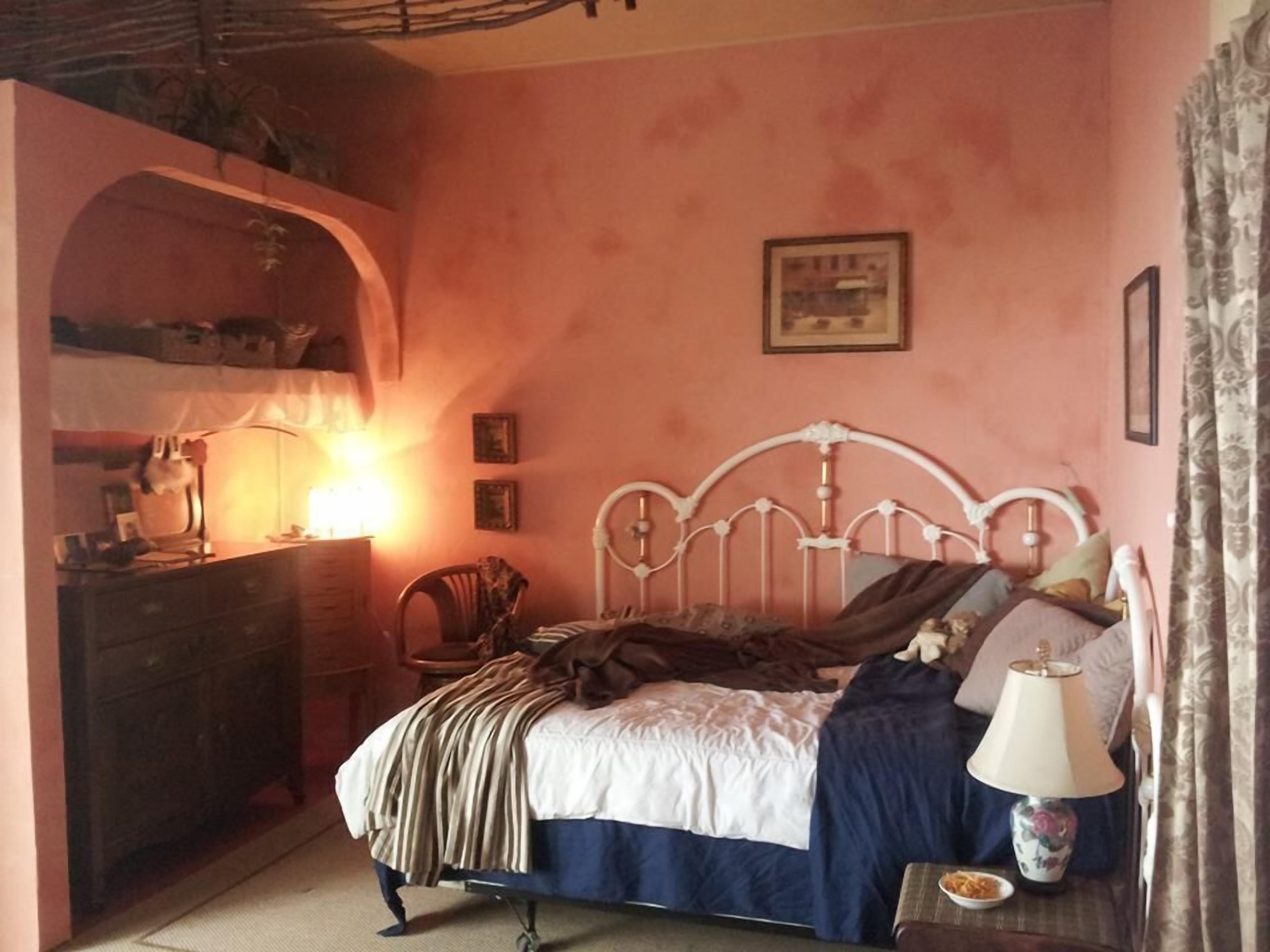 A bedroom with a bed, dresser, lamp, and a small table with a plate.