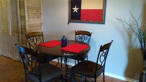 Comedor con pared de madera, una bandera de Texas y un florero con ramas.