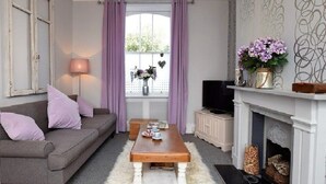A living room with a grey sofa, a wooden coffee table, a white fireplace, and a TV on a stand. - Stunning Grade II listed Holiday Home in St Leonards On-Sea (Saint Leonards-on-sea)