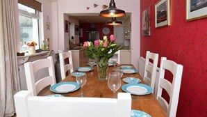 A dining room with a wooden table set for six, white chairs, and a vase of flowers. - Stunning Grade II listed Holiday Home in St Leonards On-Sea (Saint Leonards-on-sea)