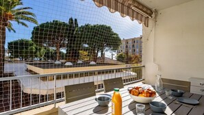 En balkon med et bord dækket til morgenmad, appelsinjuice og en skål med frugt.
