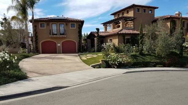A two-story house with a red garage door, a stone facade, and a landscaped garden with white flowers. - Boutique Luxury in Upscale Area with Private Entry & Bath, Villa A (SAN DIEGO)