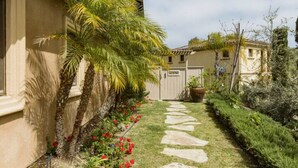 A garden with a stone pathway, palm trees, and red flowers. - Boutique Luxury in Upscale Area with Private Entry & Bath, Villa A (SAN DIEGO)