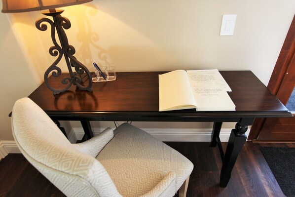 Een houten tafel met een lamp, een open boek en een glas water.