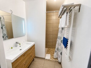A bathroom with a sink, mirror, shower, and towel rack. - Lou Meinado (Saint-Martin-de-Crau)
