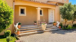 Un bâtiment à deux étages, doté d’une façade beige, d’une entrée couverte avec des marches et d’une porte.