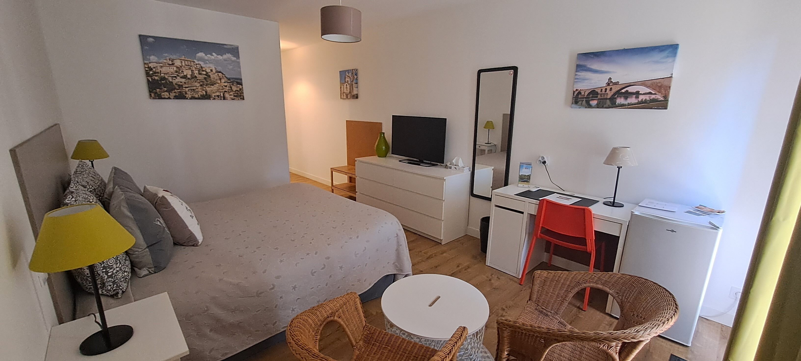 A bedroom with a bed, a desk, a chair, a television, and a mirror.