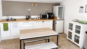 Une cuisine de taille réduite, dotée d’un plan de travail en bois, de meubles blancs, d’un petit réfrigérateur et d’un four à micro-ondes.