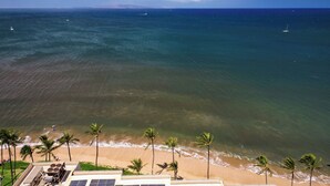 A beach view with palm trees, ocean, and boats. - Sugar Beach 102 Gorgeous Remodeled Home Beachfront Condo Home (Kihei)