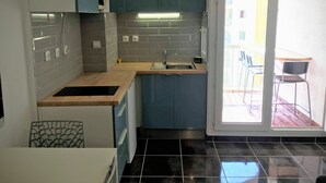 A compact kitchen with a built-in oven, a sink, and a small dining area with chairs. - Studio cabin 4 beds, sea view: beach 5 min + parking + air conditioning (Mauguio)