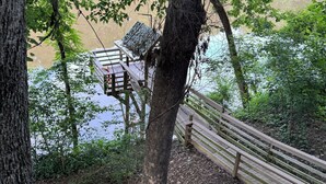 Una terraza de madera con un banco que da a un cuerpo de agua, rodeada de árboles.