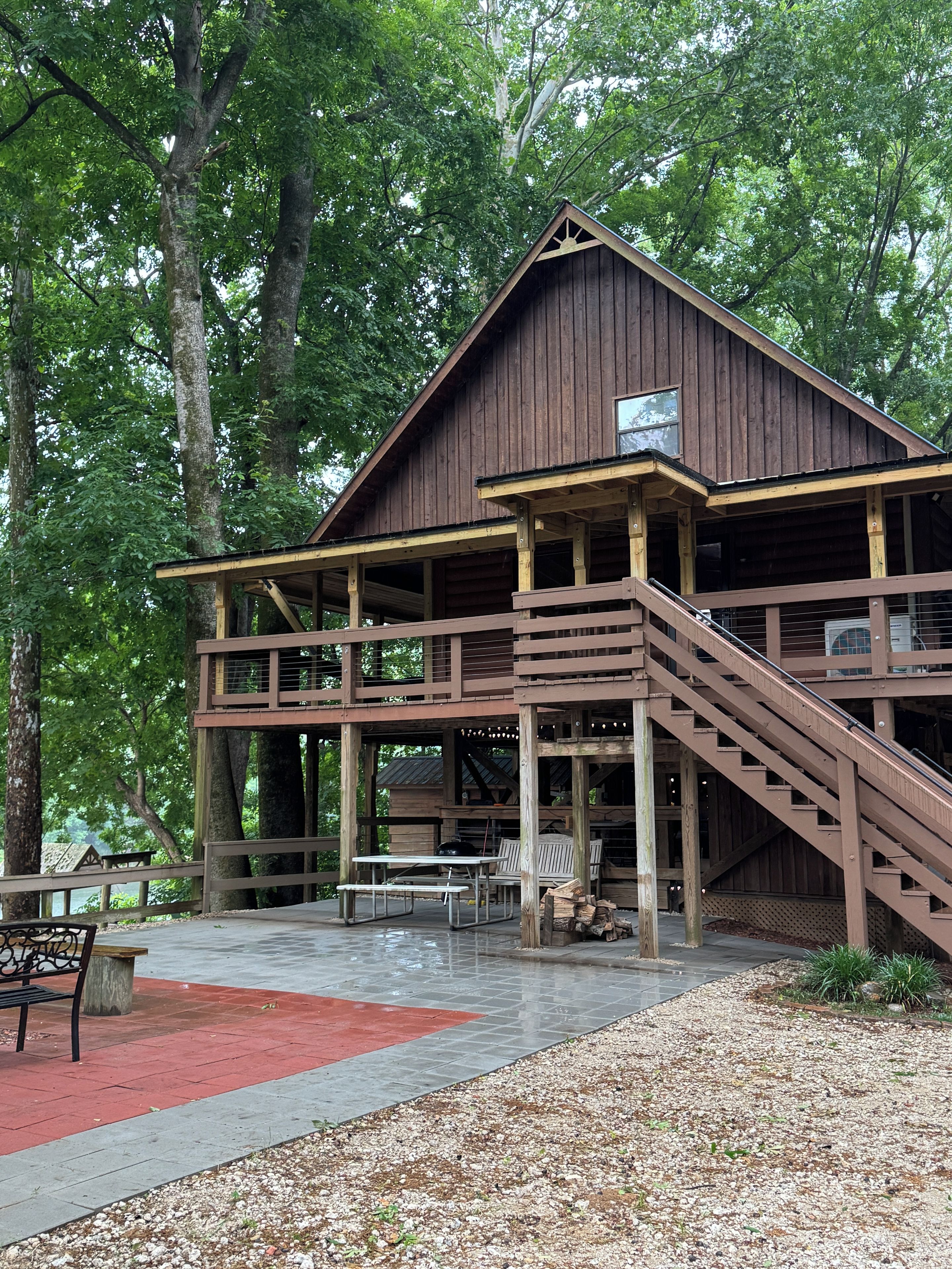 A wooden cabin with a covered porch and a staircase leading to an upper level.
