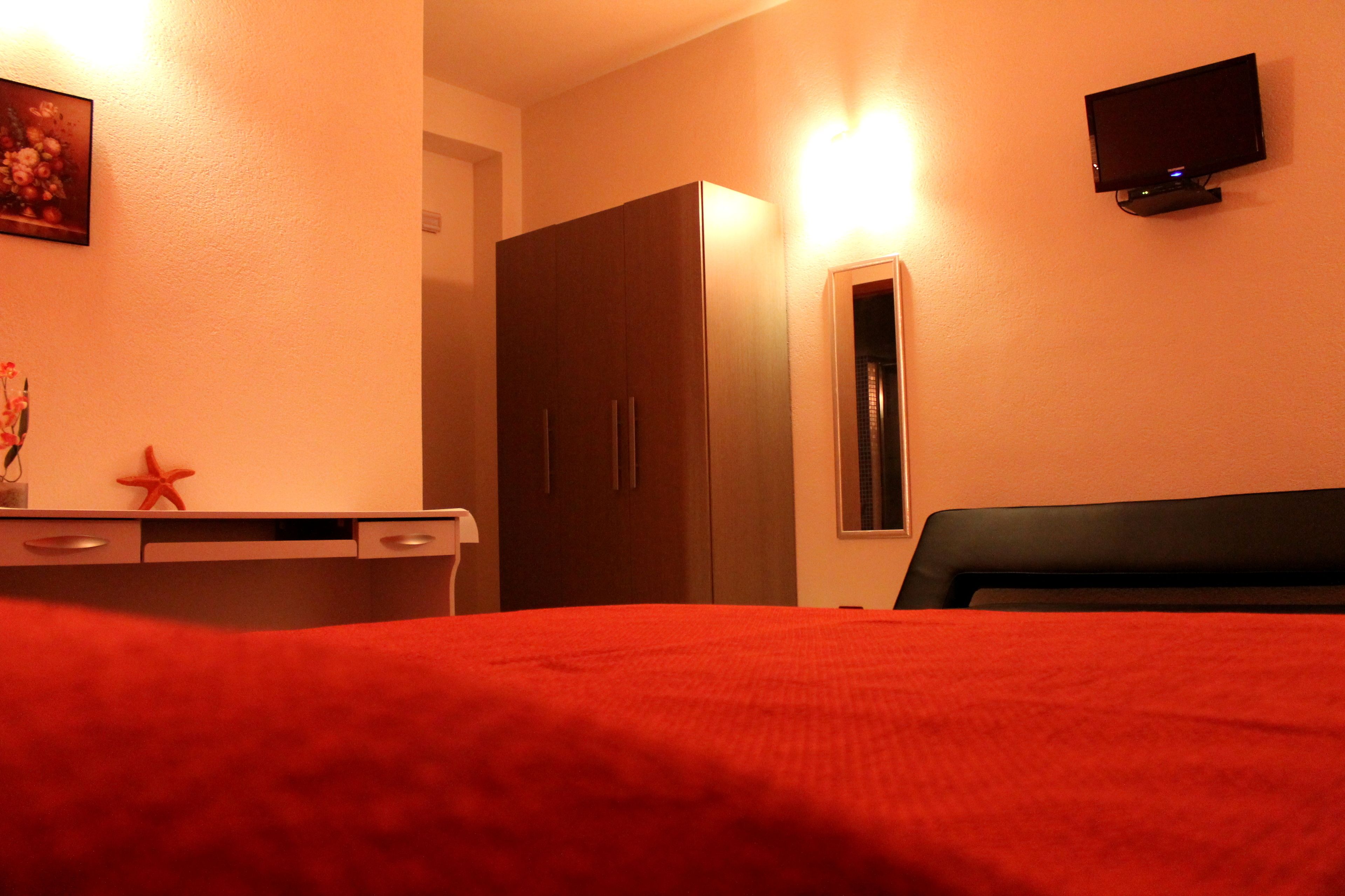 Une chambre d’hôtel équipée d’un lit, d’un bureau, d’une armoire et d’un téléviseur fixé au mur.